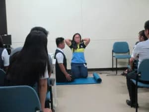 A group of employees actively participating in a physical therapy demonstration led by Ms. Loida Vidania.